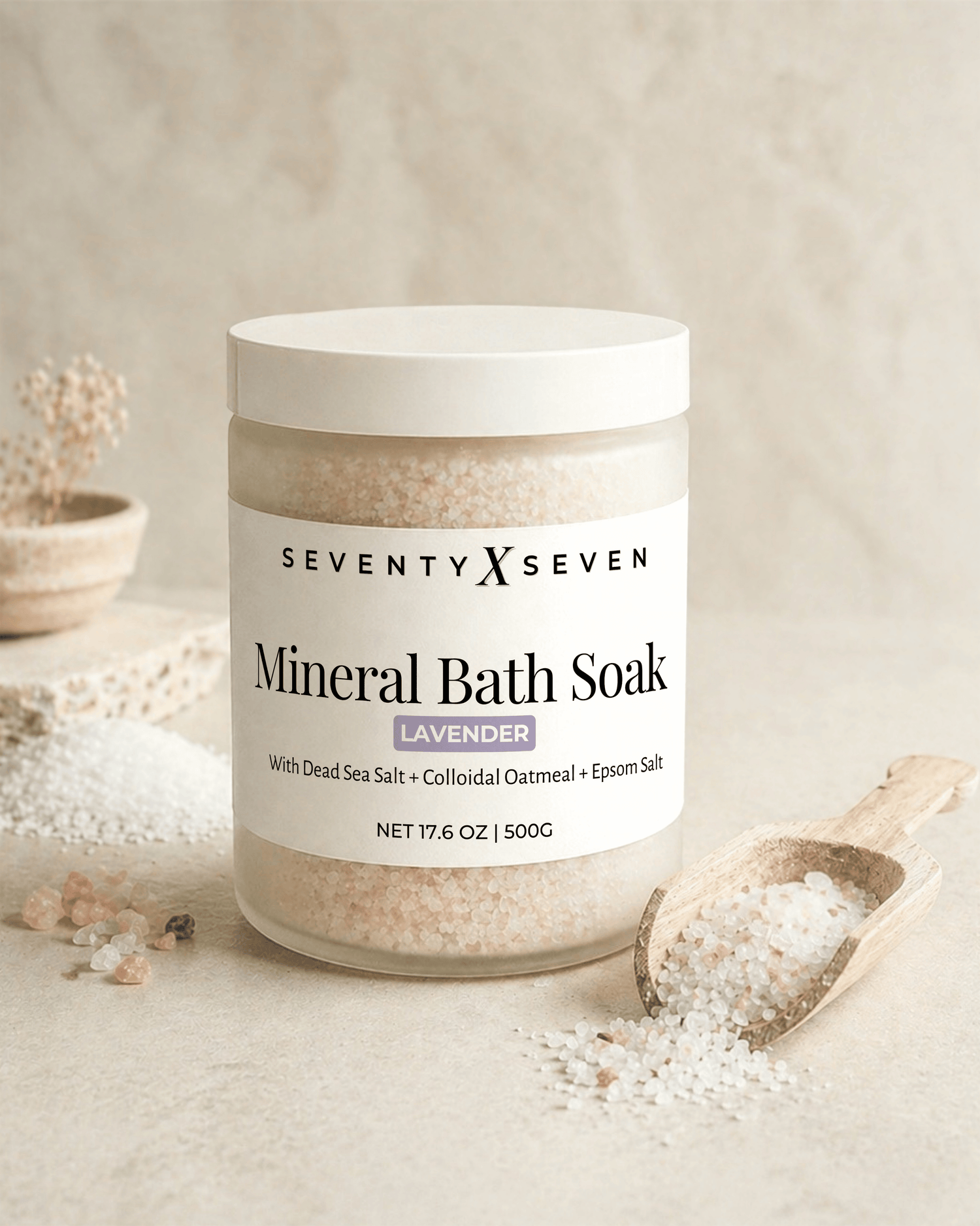 Lavender scented mineral bath salts in a large frosted glass jar with wooden scoop on neutral backdrop