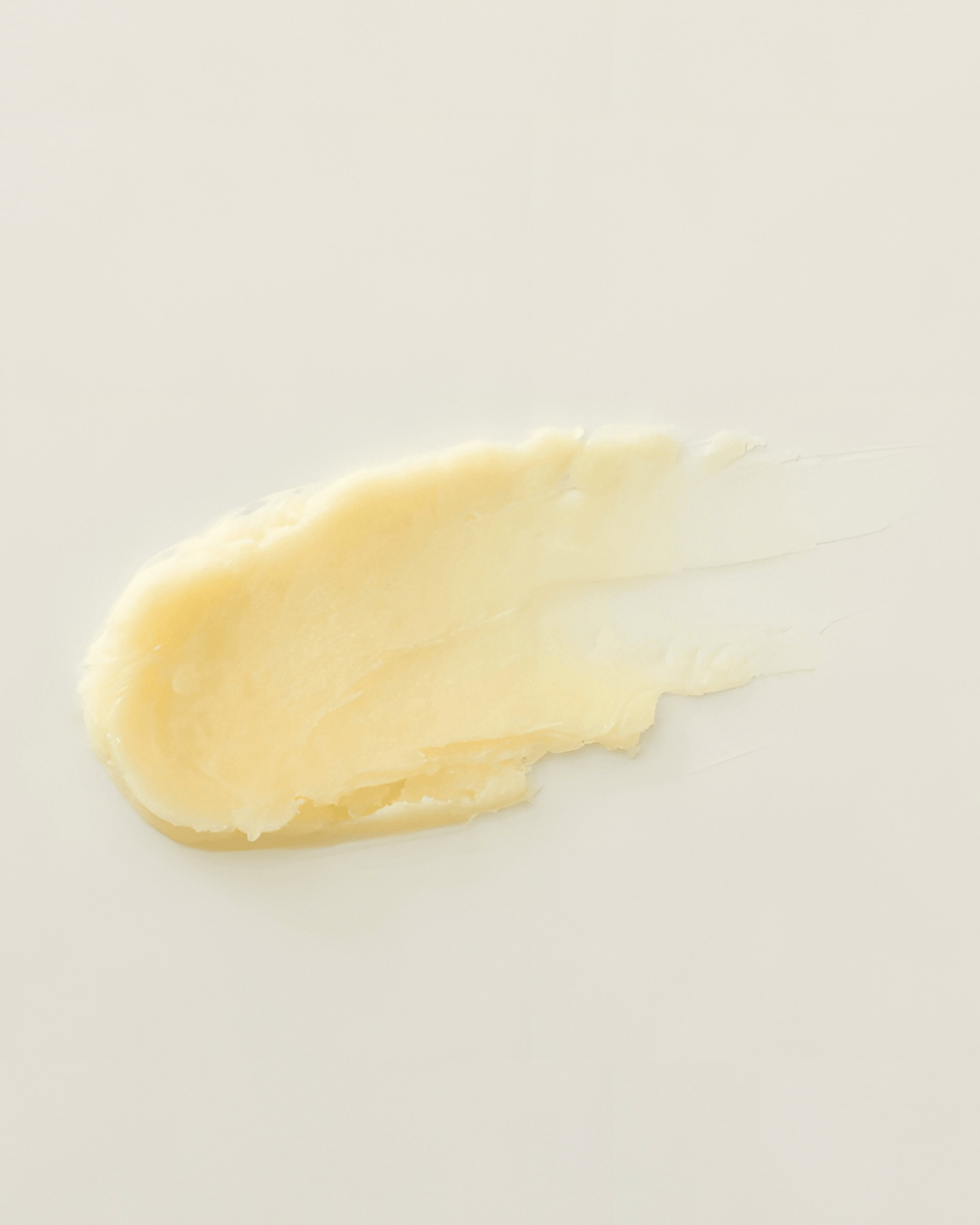 smear of yellow beeswax lip balm on neutral background
