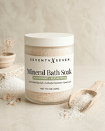 Peppermint Eucalyptus scented mineral bath salts in a large frosted glass jar with wooden scoop on neutral backdrop